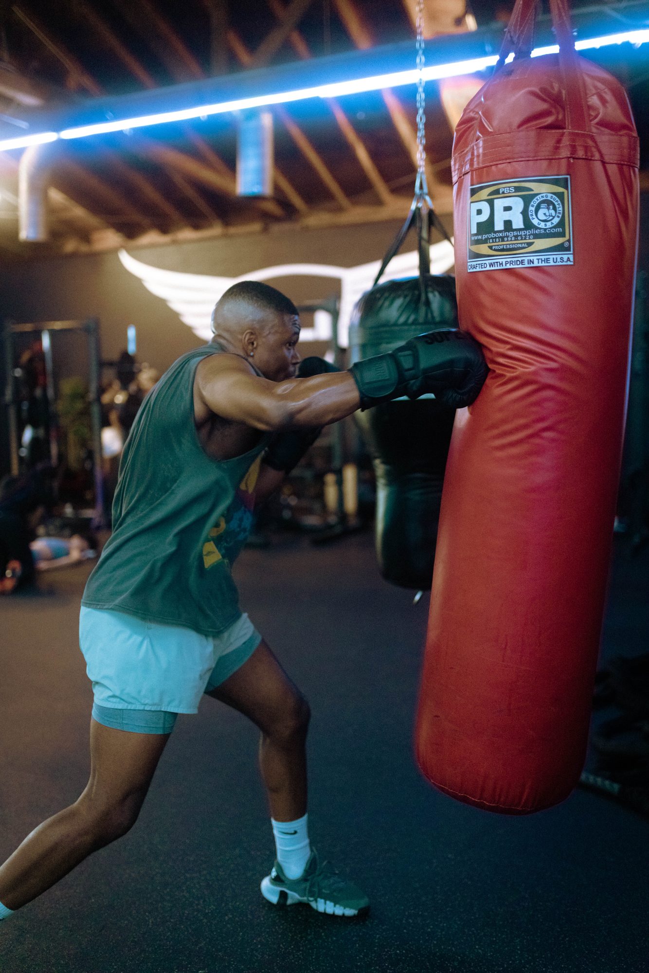 Caleb Castille boxing at a heavy bag in a neon-lit gym