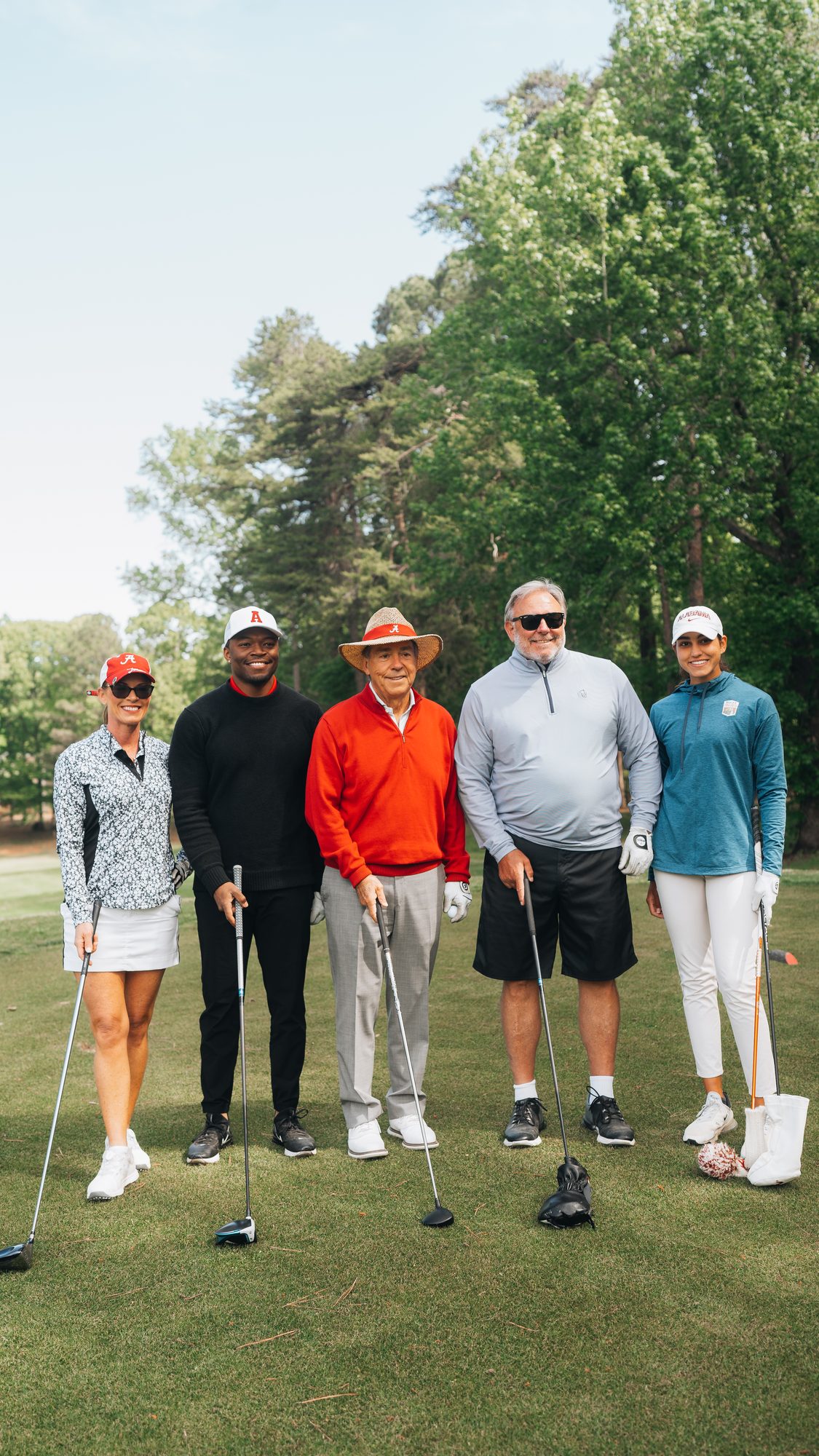 Group of five people standing with golf clubs on a golf course