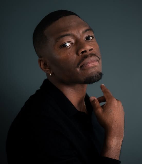Studio portrait of Caleb Castille against a slate-grey backdrop
